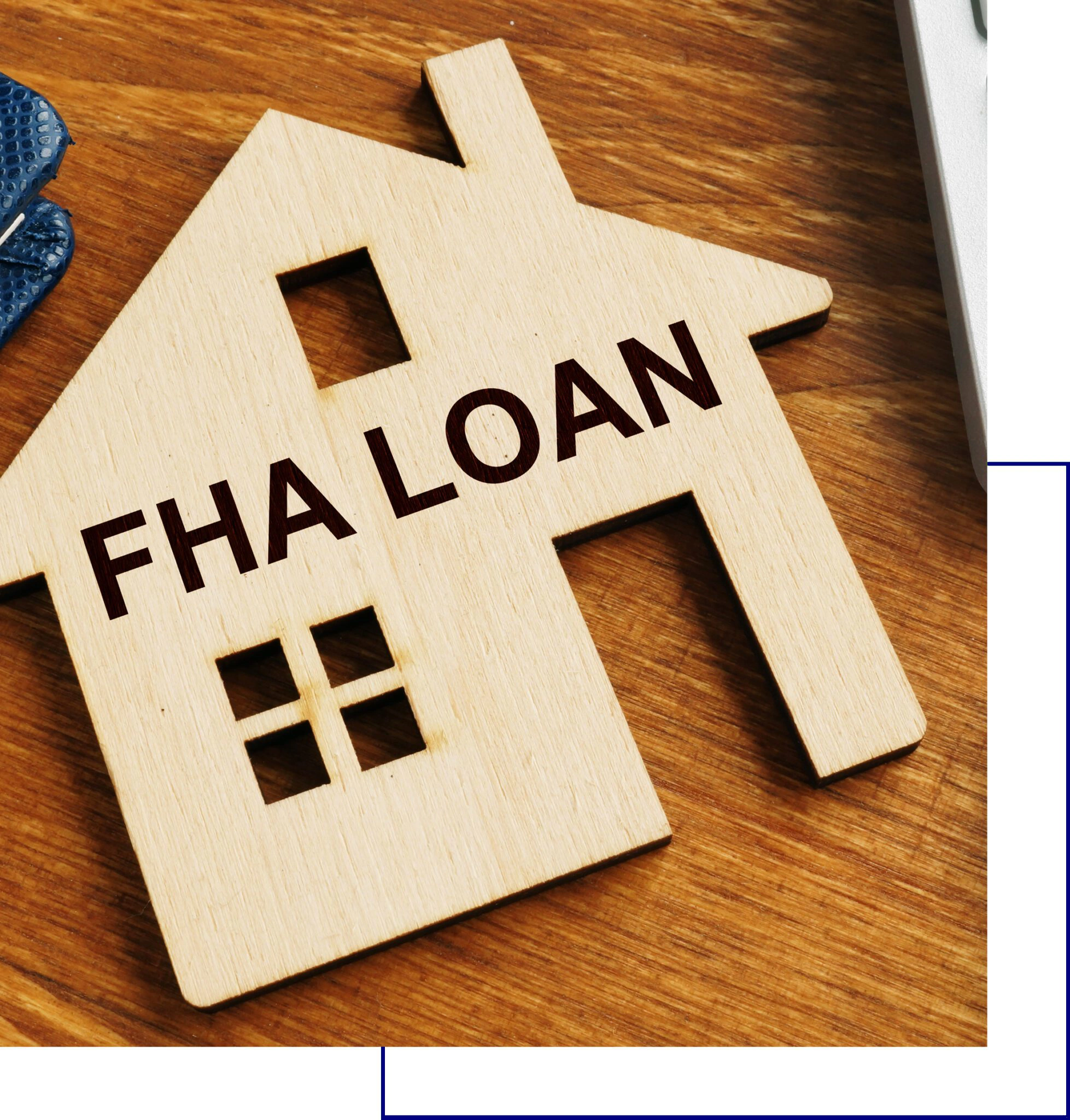 Wooden house-shaped keychain with 'FHA LOAN' text on wooden surface.