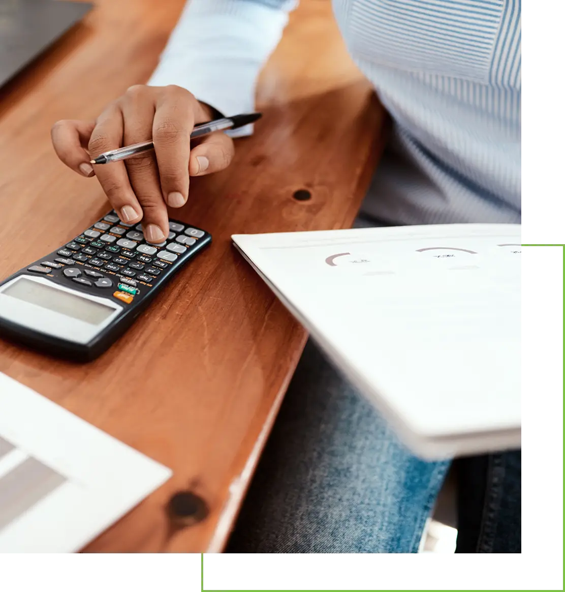 Person using a calculator and holding a pen at a desk.